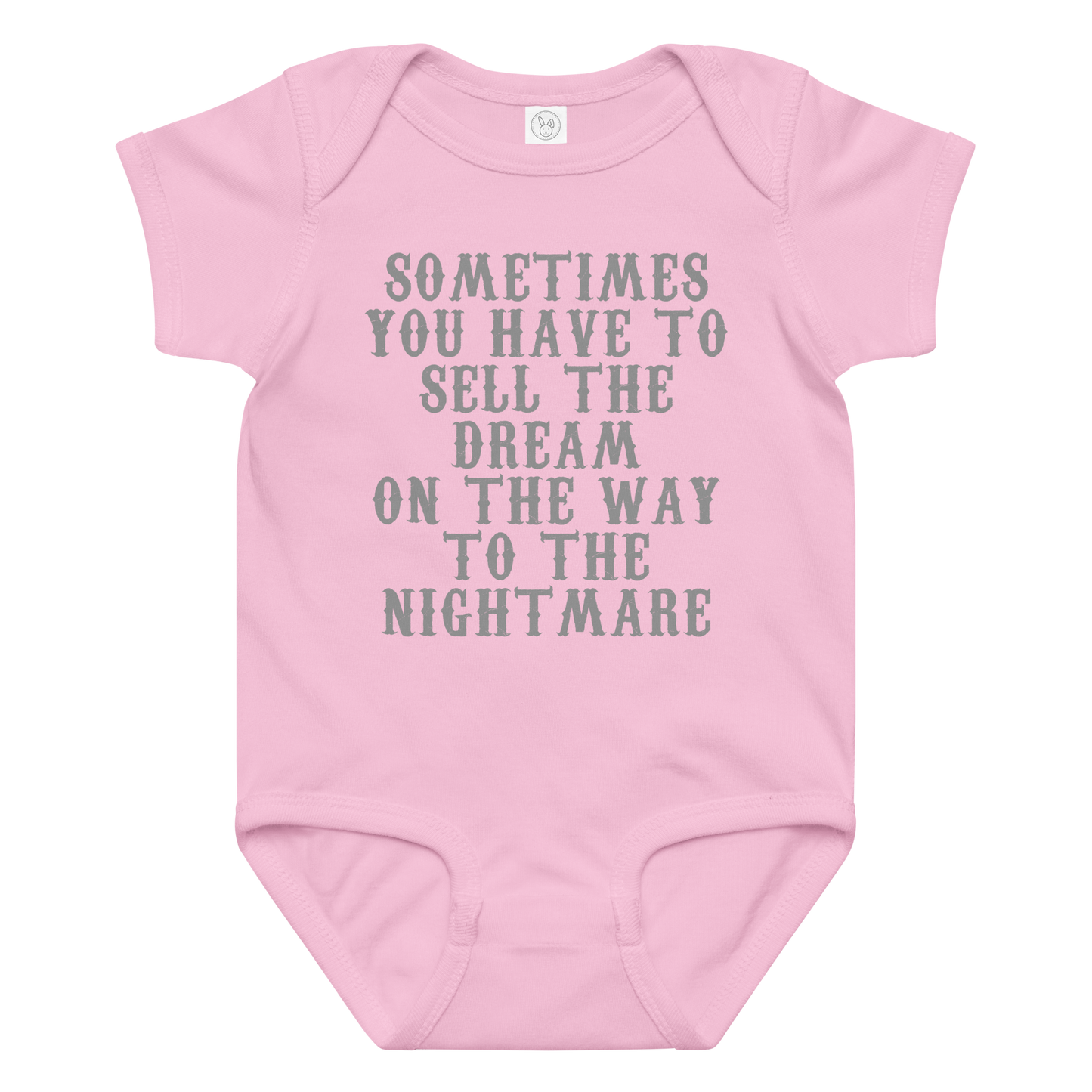 "Sometimes you have to sell the dream on the way to the nightmare" printed on a pink baby jersey bodysuit laying on a flat surface amongst other clothes