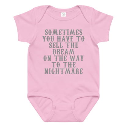 "Sometimes you have to sell the dream on the way to the nightmare" printed on a pink baby jersey bodysuit laying on a flat surface amongst other clothes