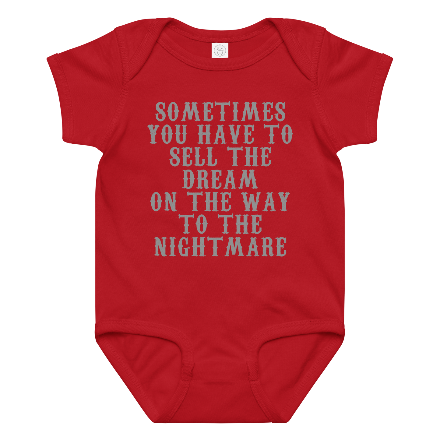 "Sometimes you have to sell the dream on the way to the nightmare" printed on a red baby jersey bodysuit laying on a flat surface amongst other clothes