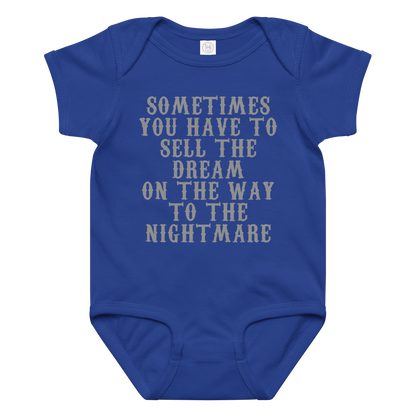 "Sometimes you have to sell the dream on the way to the nightmare" printed on a royal baby jersey bodysuit laying on a flat surface amongst other clothes