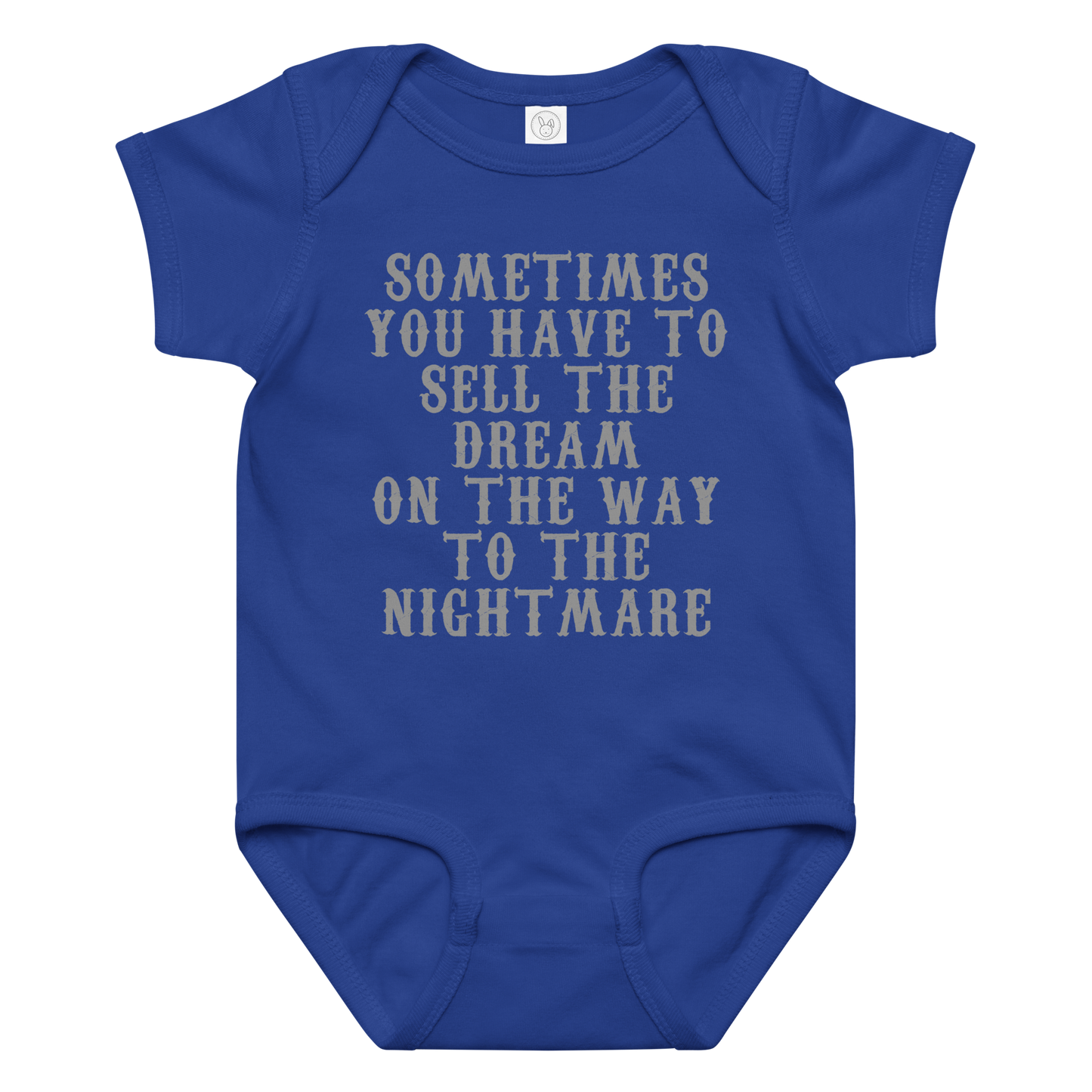 "Sometimes you have to sell the dream on the way to the nightmare" printed on a royal baby jersey bodysuit laying on a flat surface amongst other clothes