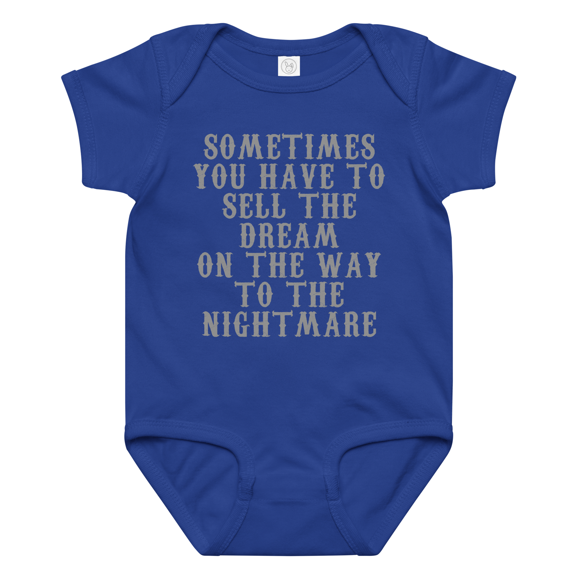"Sometimes you have to sell the dream on the way to the nightmare" printed on a royal baby jersey bodysuit laying on a flat surface amongst other clothes