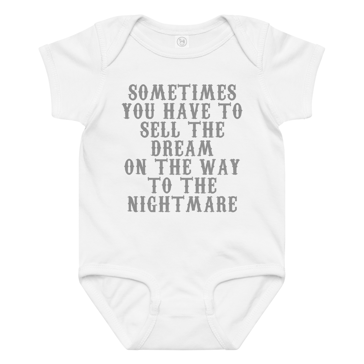 "Sometimes you have to sell the dream on the way to the nightmare" printed on a white baby jersey bodysuit laying on a flat surface amongst other clothes
