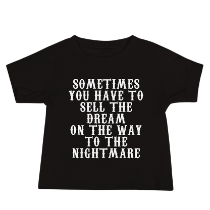 "Sometimes you have to sell the dream on the way to the nightmare" printed on a black baby jersey short sleeve tee laying on a flat surface