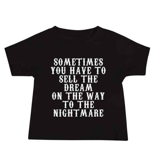"Sometimes you have to sell the dream on the way to the nightmare" printed on a black baby jersey short sleeve tee laying on a flat surface