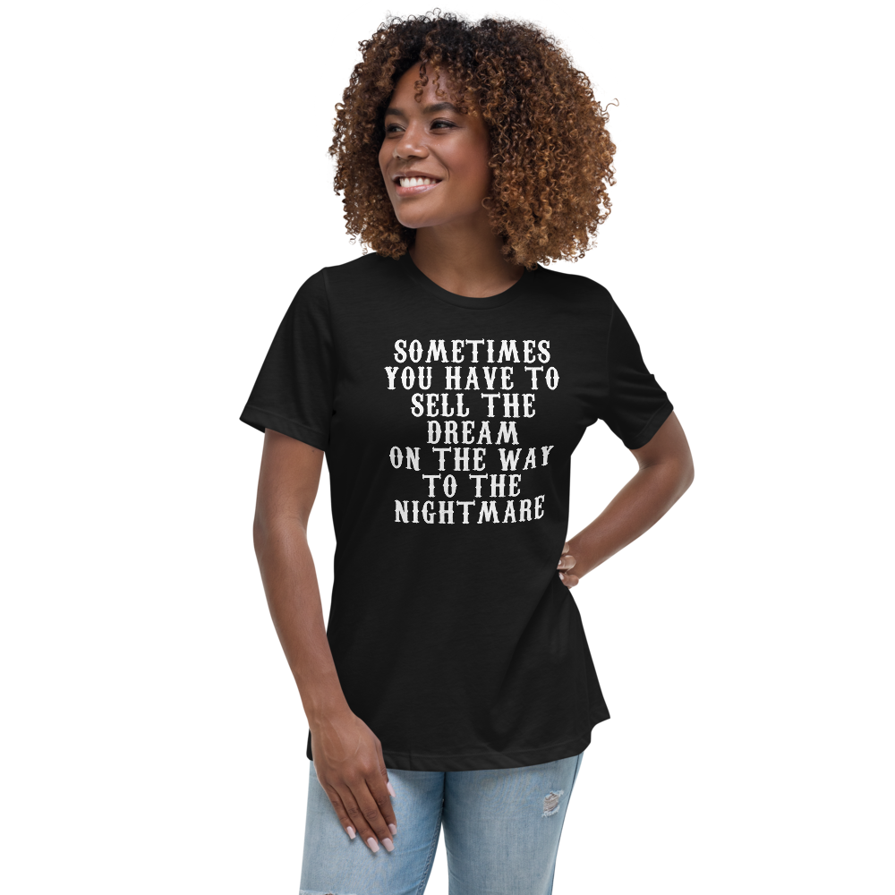 "Sometimes you have to sell the dream on the way to the nightmare" printed on a black women's relaxed t-shirt worn by a female
