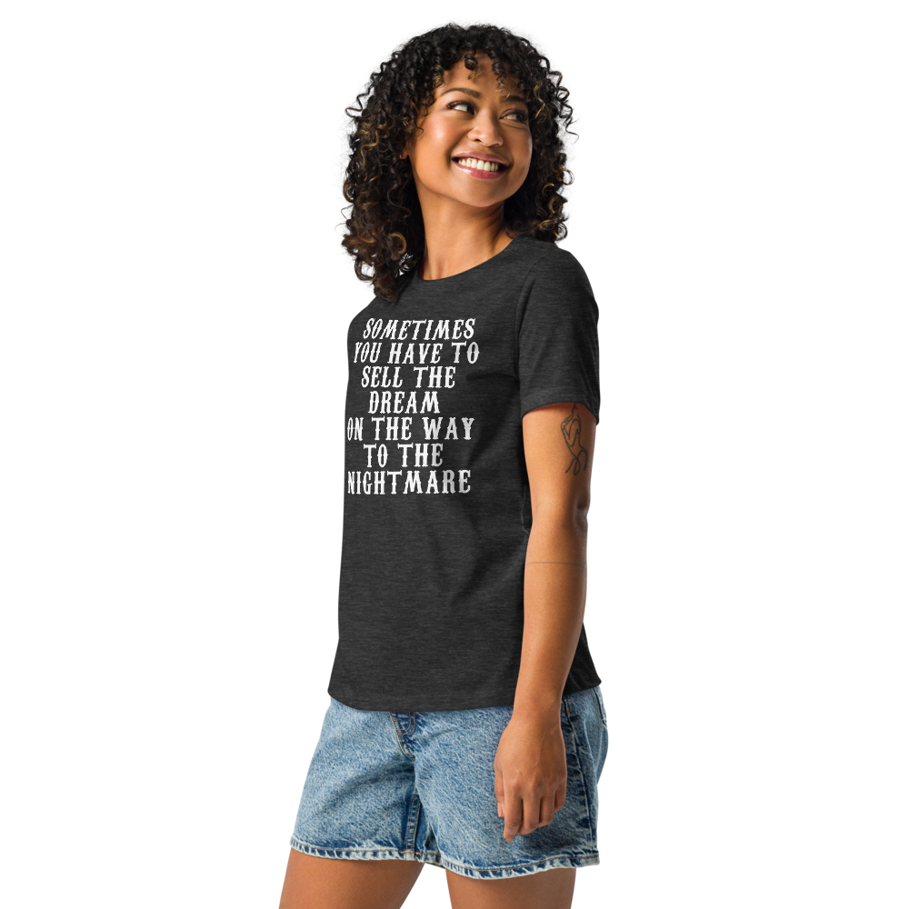 "Sometimes you have to sell the dream on the way to the nightmare" printed on a dark grey heather women's relaxed t-shirt worn by a female