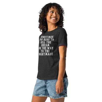 "Sometimes you have to sell the dream on the way to the nightmare" printed on a dark grey heather women's relaxed t-shirt worn by a female