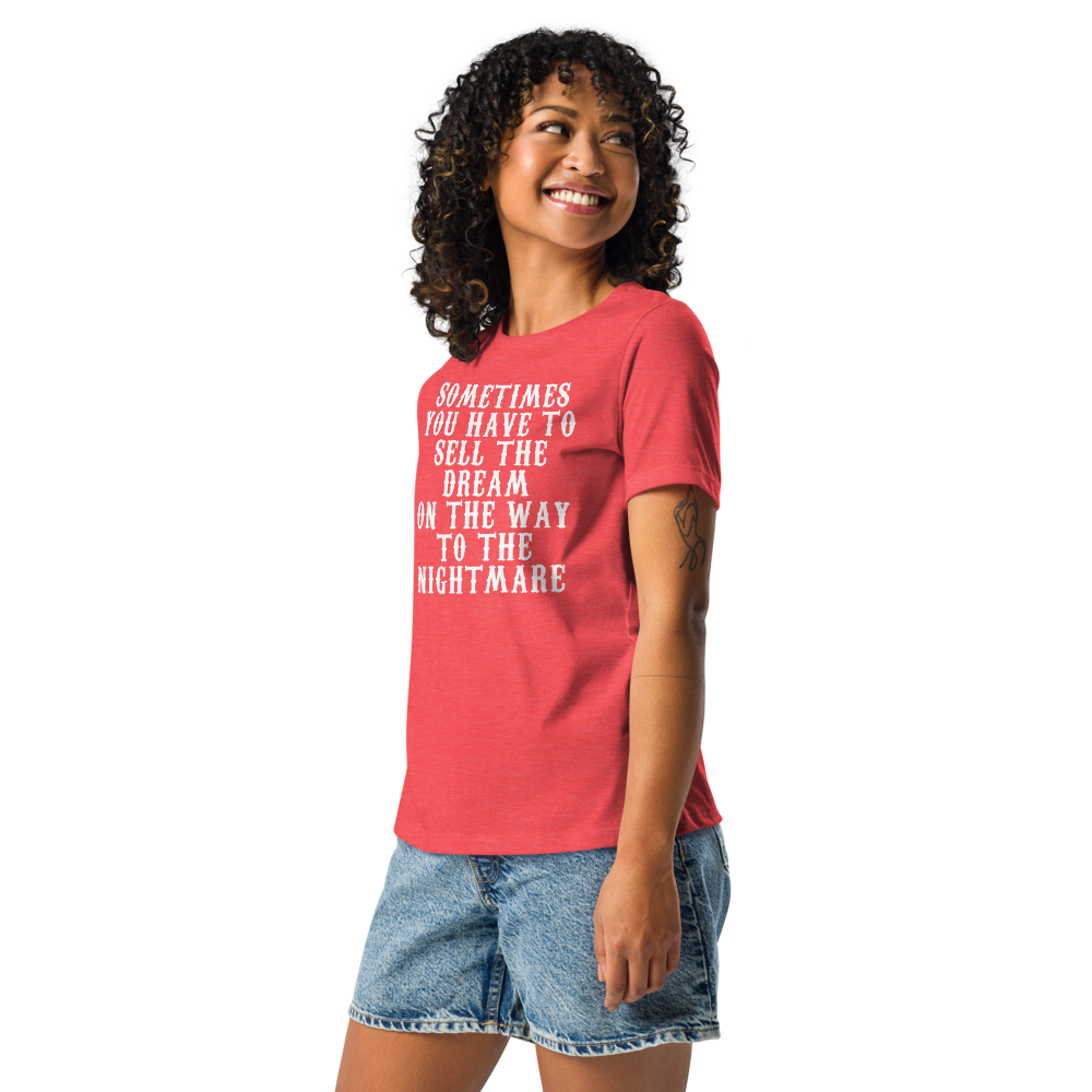 "Sometimes you have to sell the dream on the way to the nightmare" printed on a heather red women's relaxed t-shirt worn by a female