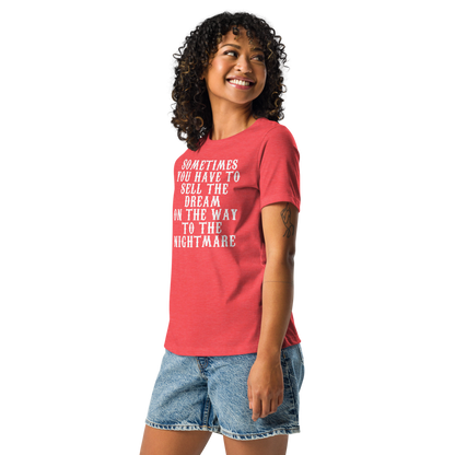 "Sometimes you have to sell the dream on the way to the nightmare" printed on a heather red women's relaxed t-shirt worn by a female