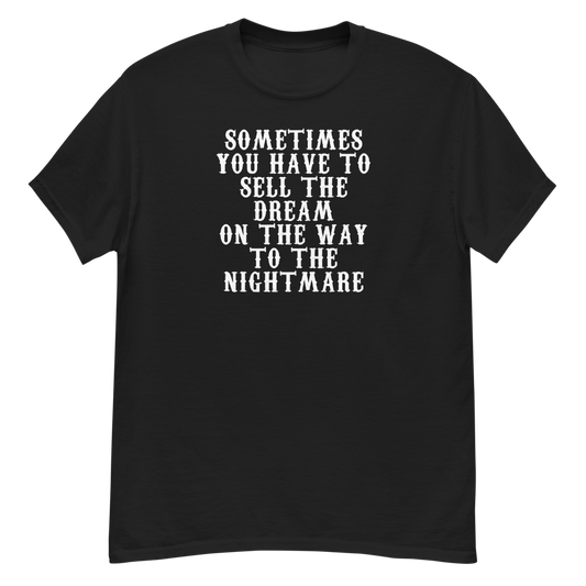 "Sometimes you have to sell the dream on the way to the nightmare" printed on a black unisex classic tee laying on a flat surface