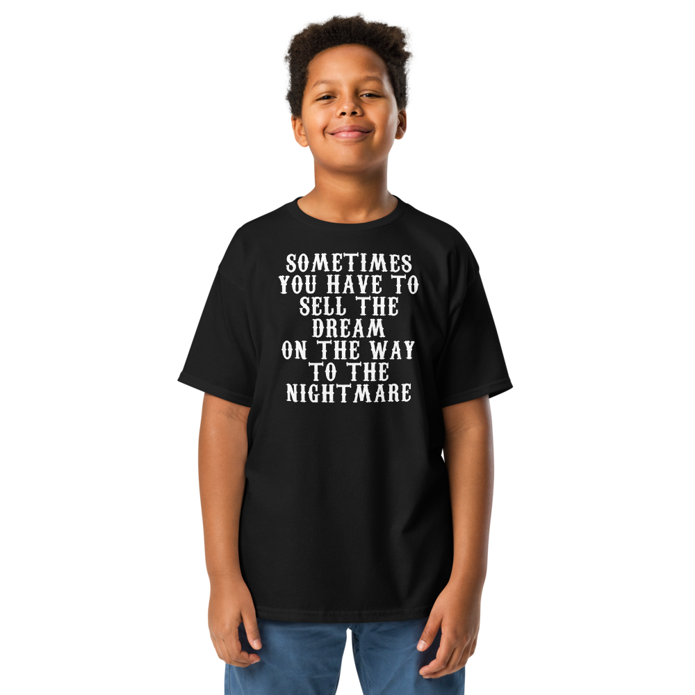 "Sometimes you have to sell the dream on the way to the nightmare" printed on a black youth classic tee worn by a male