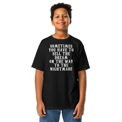"Sometimes you have to sell the dream on the way to the nightmare" printed on a black youth classic tee worn by a male