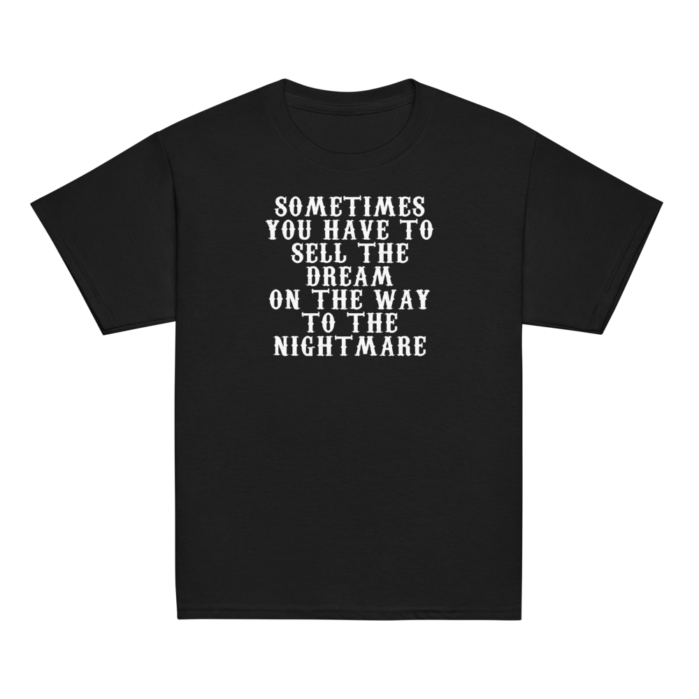 "Sometimes you have to sell the dream on the way to the nightmare" printed on a black youth classic tee laying on a flat surface