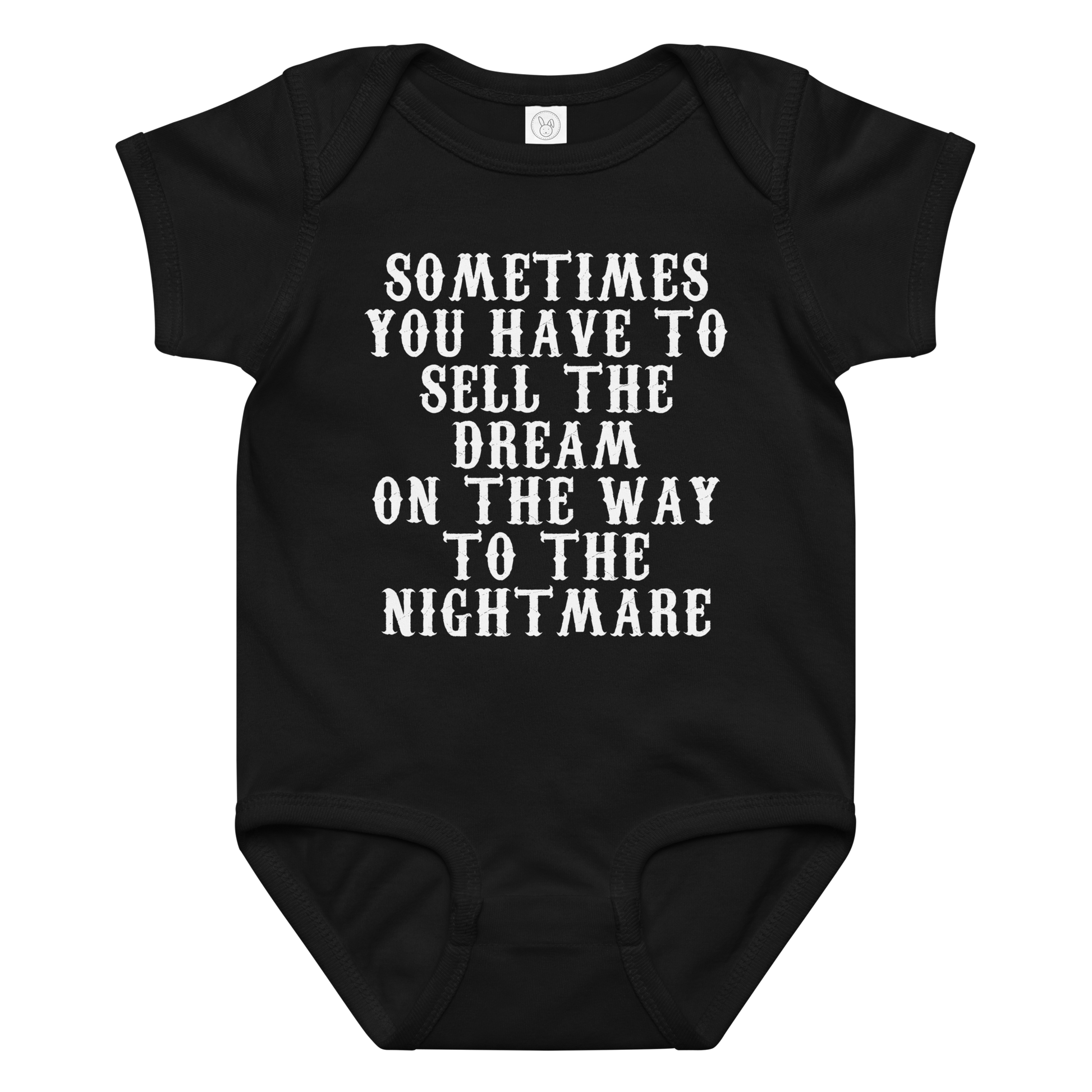 "Sometimes you have to sell the dream on the way to the nightmare" printed on a black baby jersey bodysuit laying on a flat surface amongst other clothes