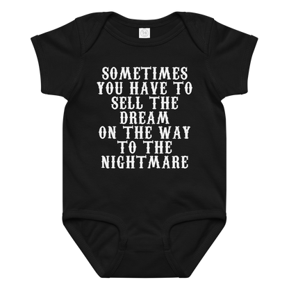 "Sometimes you have to sell the dream on the way to the nightmare" printed on a black baby jersey bodysuit laying on a flat surface amongst other clothes