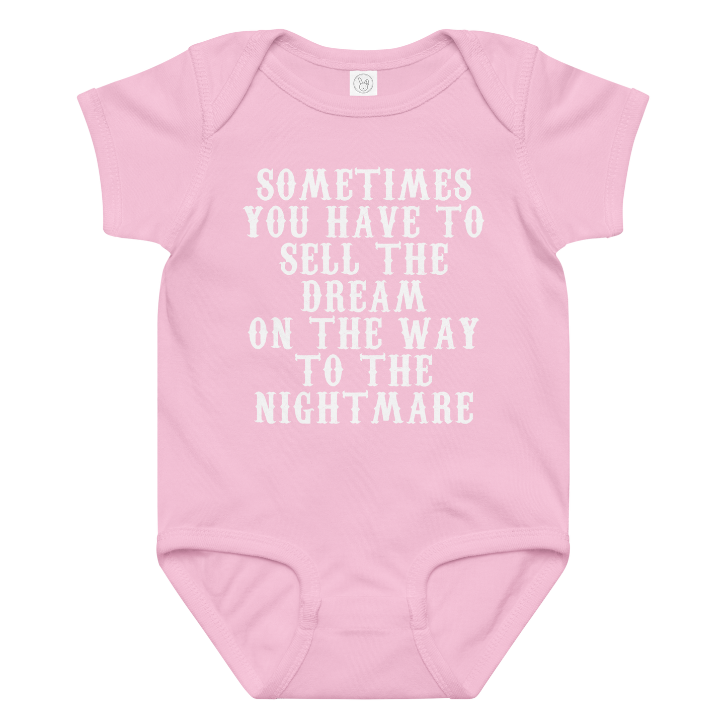 "Sometimes you have to sell the dream on the way to the nightmare" printed on a pink baby jersey bodysuit laying on a flat surface amongst other clothes