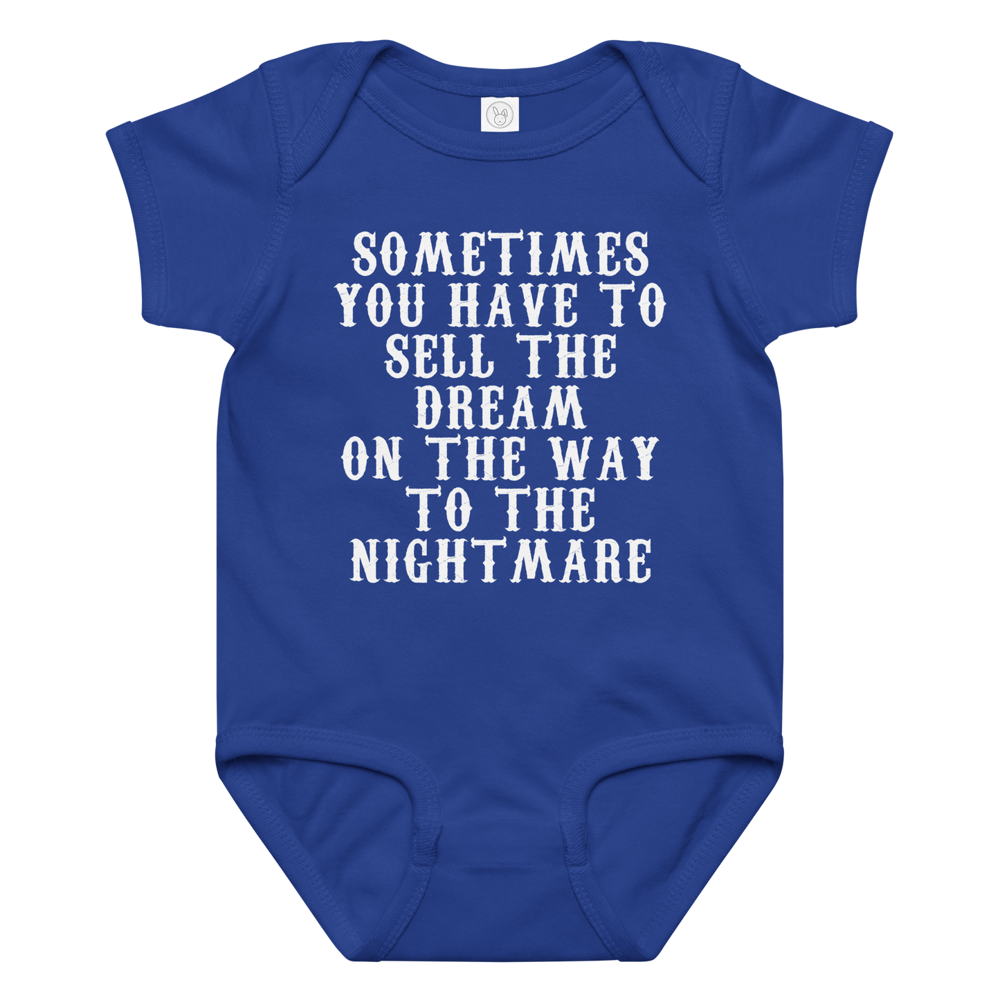 "Sometimes you have to sell the dream on the way to the nightmare" printed on a royal baby jersey bodysuit laying on a flat surface amongst other clothes