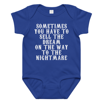 "Sometimes you have to sell the dream on the way to the nightmare" printed on a royal baby jersey bodysuit laying on a flat surface amongst other clothes