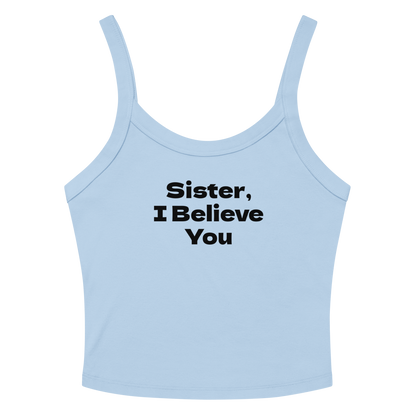 "Sister, I Believe You!" printed on a solid baby blue blend women's micro-rib tanktop laying on a flat surface amongst sunglasses and shorts