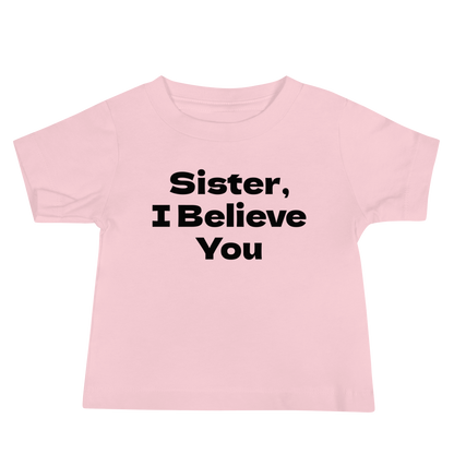 "Sister, I Believe You!" printed on a pink baby jersey short sleeve tee laying on a flat surface