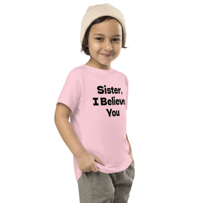 "Sister, I Believe You!" printed on a pink toddler short sleeve tee worn by a male who is also wearing a knit cap