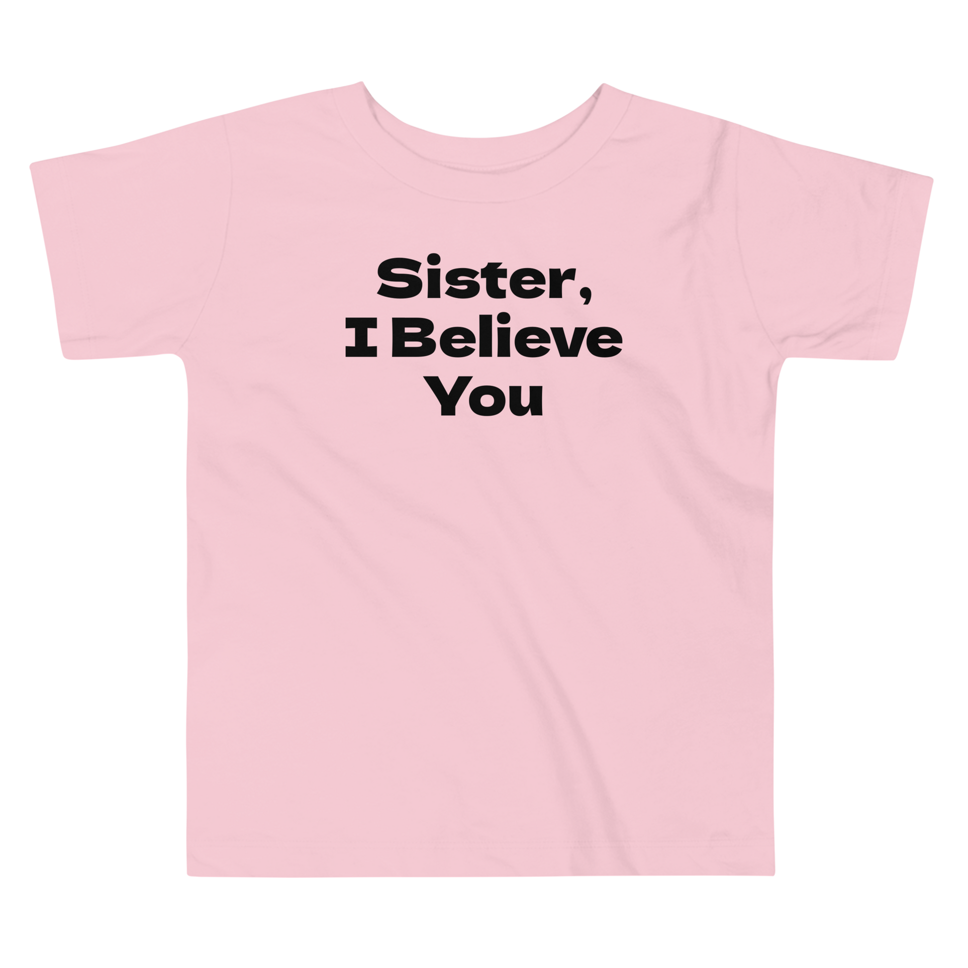 "Sister, I Believe You!" printed on a pink toddler short sleeve tee laying on a flat surface