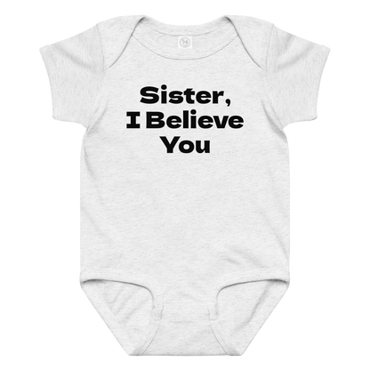 "Sister, I Believe You!" printed on a ash baby jersey bodysuit laying on a flat surface amongst other clothes