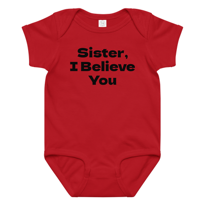 "Sister, I Believe You!" printed on a red baby jersey bodysuit laying on a flat surface amongst other clothes