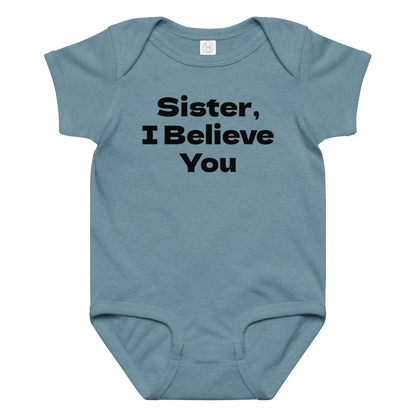 "Sister, I Believe You!" printed on a vintage indigo baby jersey bodysuit laying on a flat surface amongst other clothes