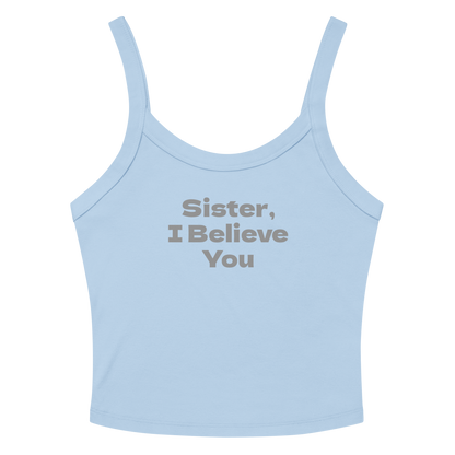"Sister, I Believe You!" printed on a solid baby blue blend women's micro-rib tanktop laying on a flat surface amongst sunglasses and shorts
