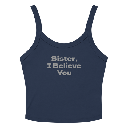 "Sister, I Believe You!" printed on a solid navy blend women's micro-rib tanktop laying on a flat surface amongst sunglasses and shorts