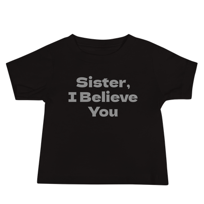 "Sister, I Believe You!" printed on a black baby jersey short sleeve tee laying on a flat surface