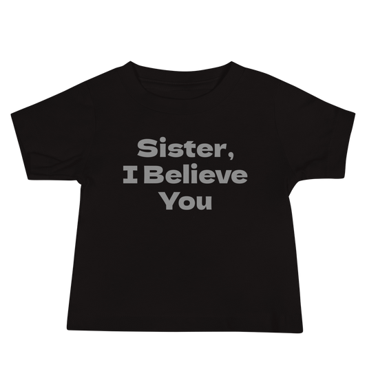 "Sister, I Believe You!" printed on a black baby jersey short sleeve tee laying on a flat surface