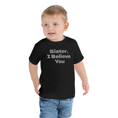 "Sister, I Believe You!" printed on a black toddler short sleeve tee worn by a male
