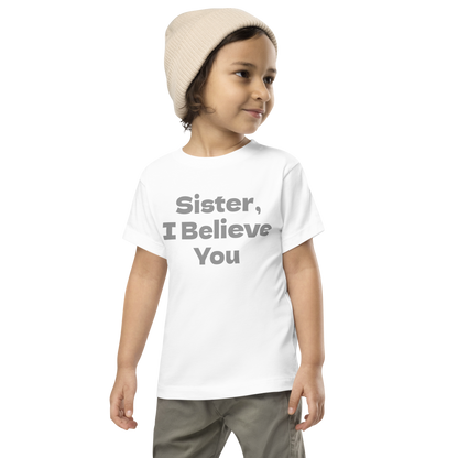 "Sister, I Believe You!" printed on a white toddler short sleeve tee worn by a male wearing a cap