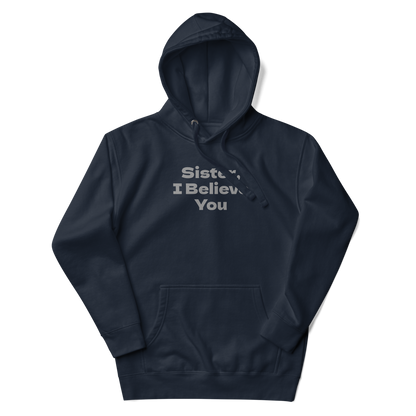 "Sister, I Believe You!" printed on a navy blazer unisex hoodie laying on a flat surface with the hood up