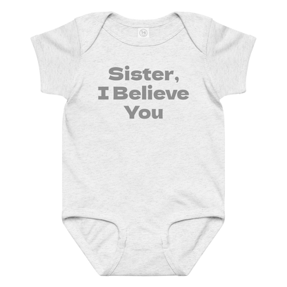 "Sister, I Believe You!" printed on a ash baby jersey bodysuit laying on a flat surface amongst other clothes