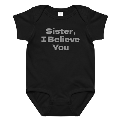 "Sister, I Believe You!" printed on a black baby jersey bodysuit laying on a flat surface amongst other clothes