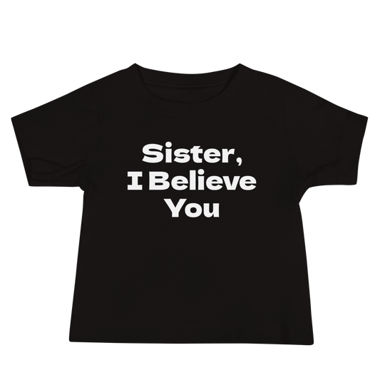 "Sister, I Believe You!" printed on a black baby jersey short sleeve tee laying on a flat surface