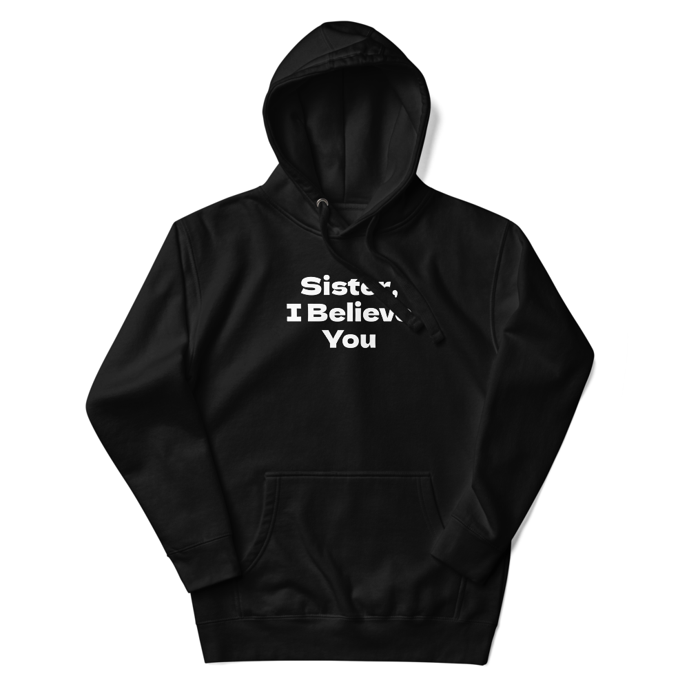 "Sister, I Believe You!" printed on a black unisex hoodie laying on a flat surface with the hood up