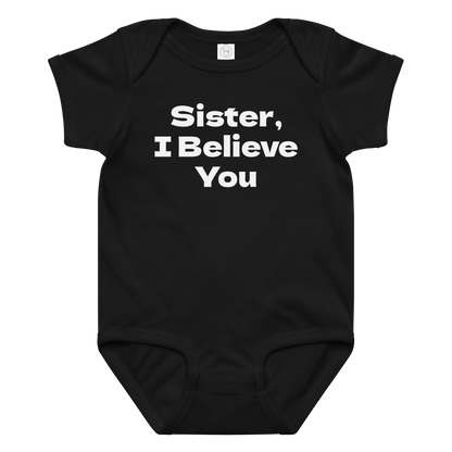 "Sister, I Believe You!" printed on a black baby jersey bodysuit laying on a flat surface amongst other clothes