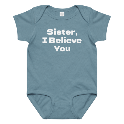 "Sister, I Believe You!" printed on a vintage indigo baby jersey bodysuit laying on a flat surface amongst other clothes