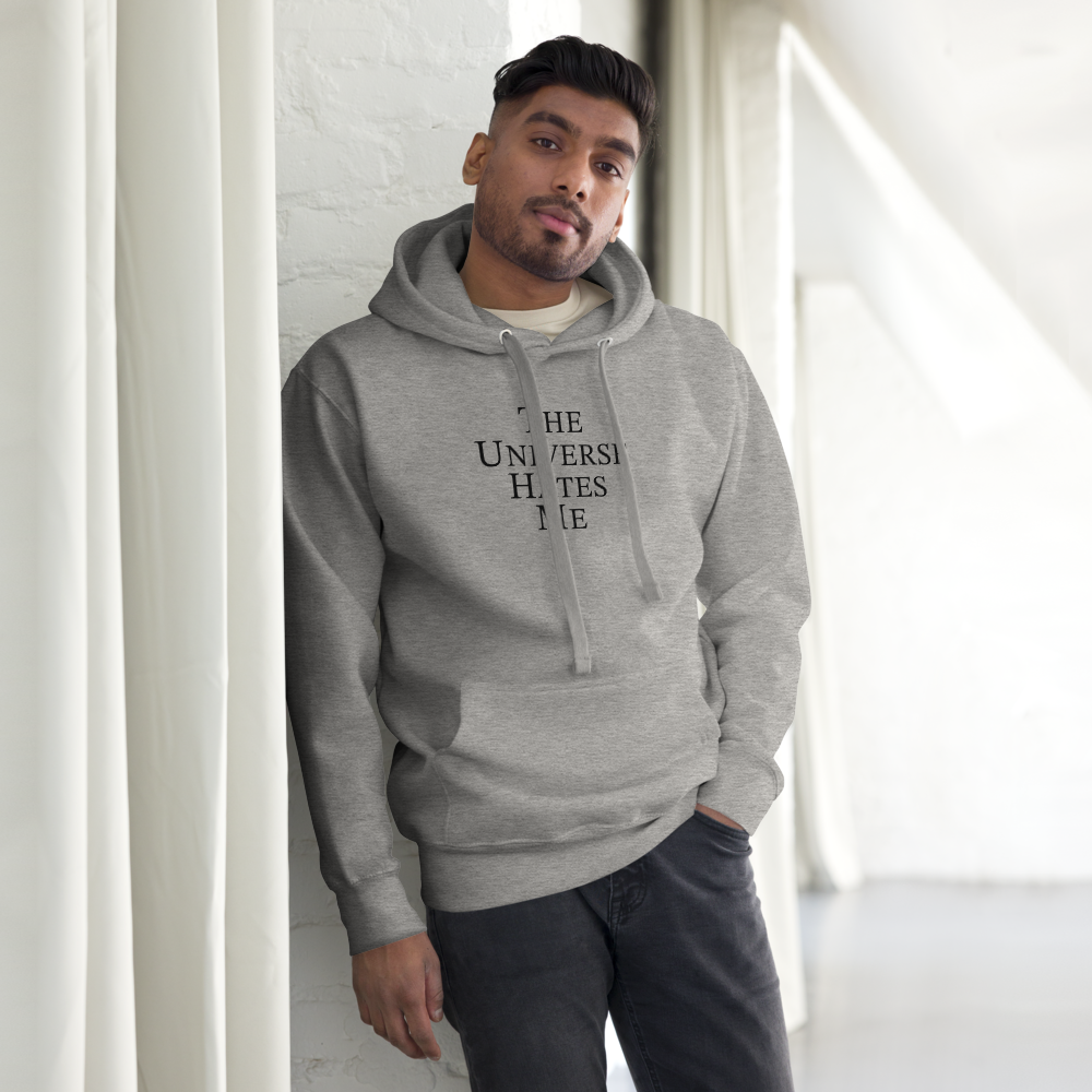 "The Universe Hates Me" printed on a carbon grey unisex hoodie worn by a male
