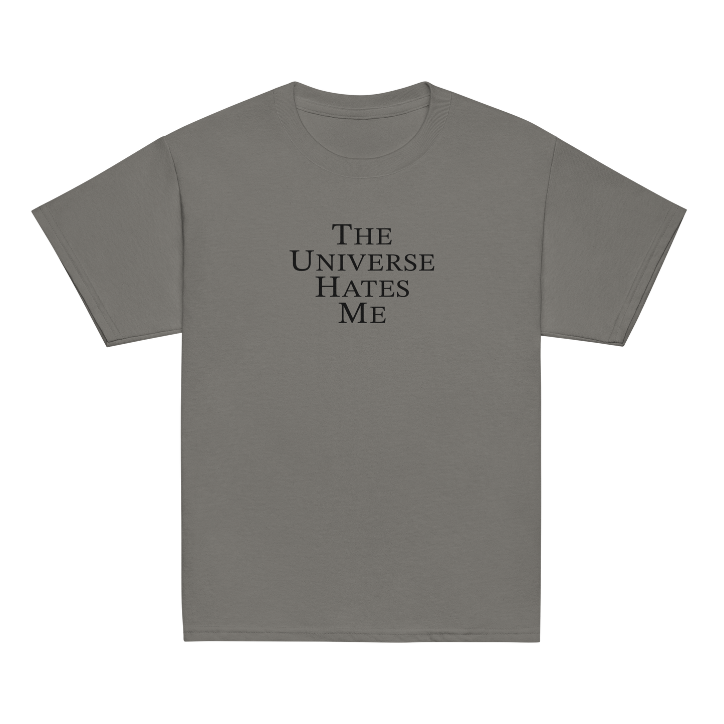 "The Universe Hates Me" printed on a charcoal youth classic tee laying on a flat surface