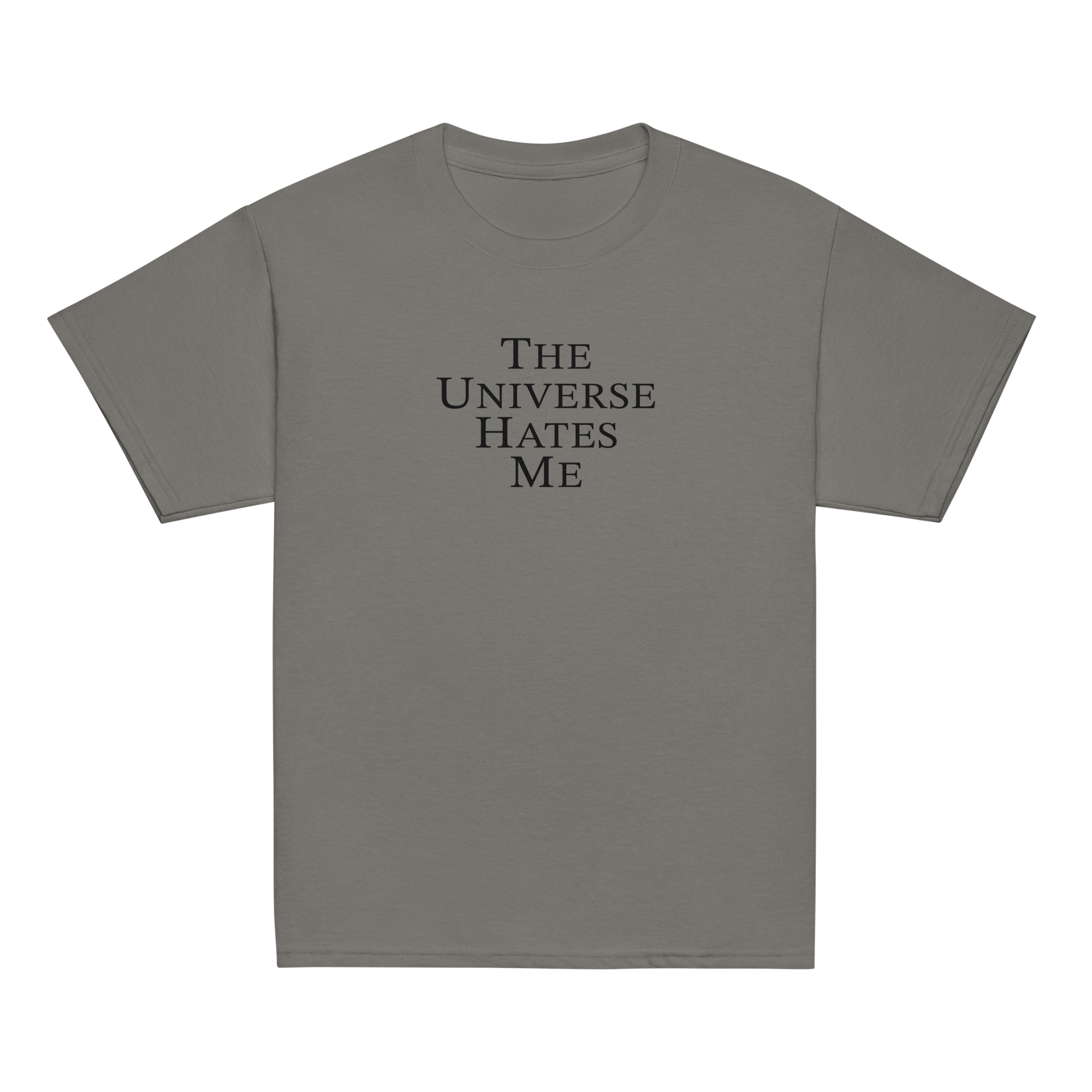 "The Universe Hates Me" printed on a charcoal youth classic tee laying on a flat surface