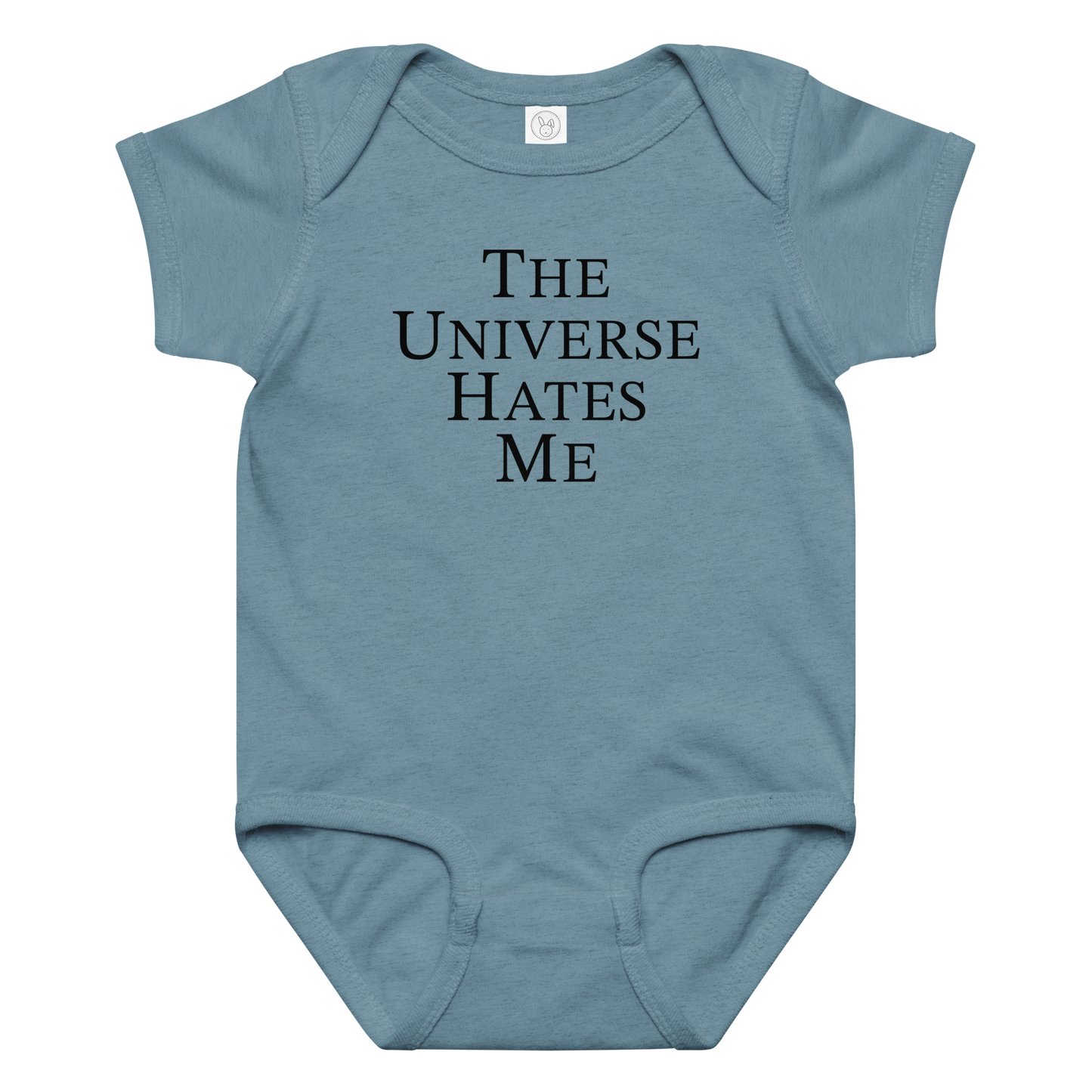 "The Universe Hates Me" printed on a vintage indigo baby jersey bodysuit laying on a flat surface amongst other clothes