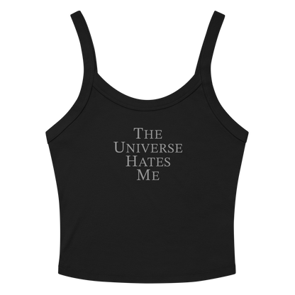 "The Universe Hates Me" printed on a solid black blend women's micro-rib tanktop laying on a flat surface amongst sunglasses and shorts