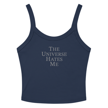 "The Universe Hates Me" printed on a solid navy blend women's micro-rib tanktop laying on a flat surface amongst sunglasses and shorts