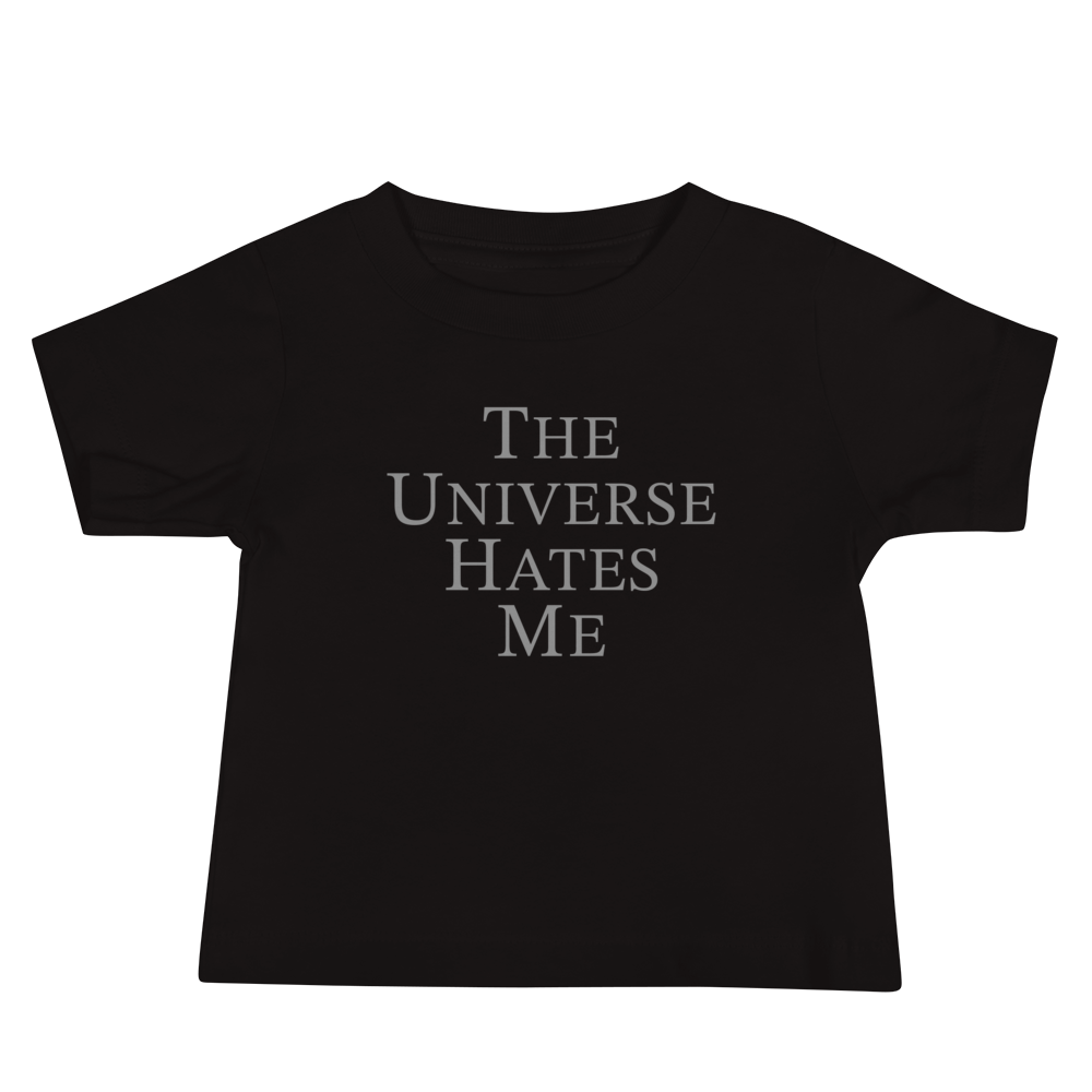 "The Universe Hates Me" printed on a black baby jersey short sleeve tee laying on a flat surface